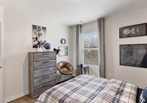 A bedroom with a plaid bedspread and a wooden dresser at The Summit Townhomes in Tennessee 37830