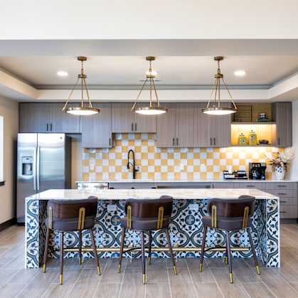 A kitchen with a checkered tile backsplash and a bar area with bar stools.