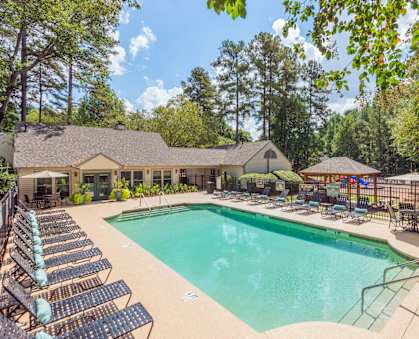 A large swimming pool surrounded by lounge chairs and umbrellas. at Woodwinds, Aiken, 29803