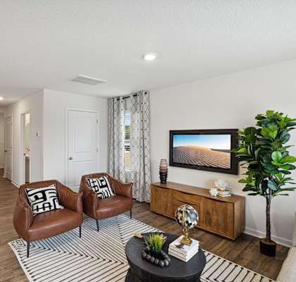 A living room with a refrigerator, two chairs, a sofa, a coffee table, and a potted plant. at The Summit Townhomes in TN 37830