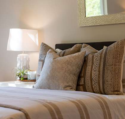 a bed with pillows and a table with a lamp at Platt Gardens, West Babylon, New York 11704
