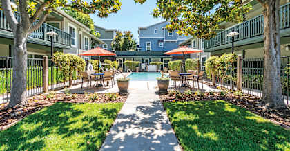 a courtyard with tables and umbrellas and a swimming pool  at Pleasanton Glen Apartments, California, 94566