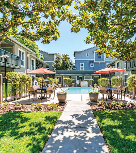 a courtyard with tables and umbrellas and a swimming pool  at Pleasanton Glen Apartments, California, 94566