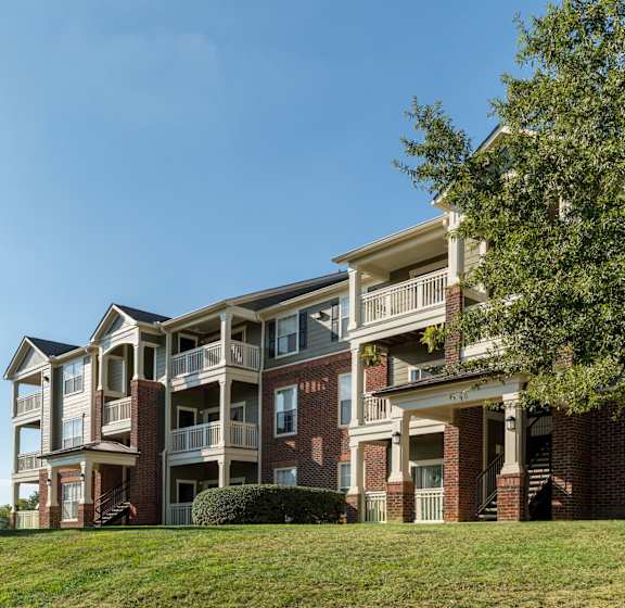 A large apartment building with a green lawn in front.