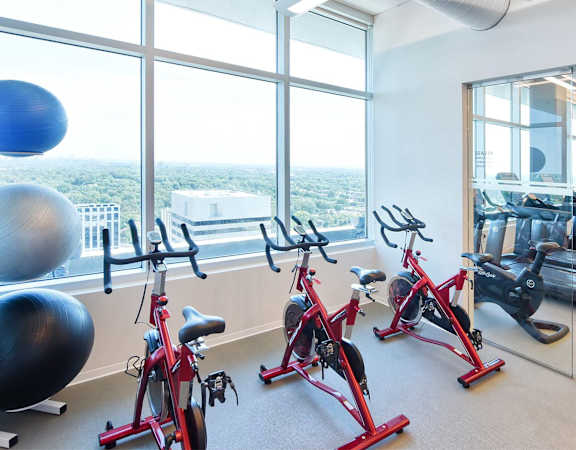 A gym with exercise bikes and a view of the city.