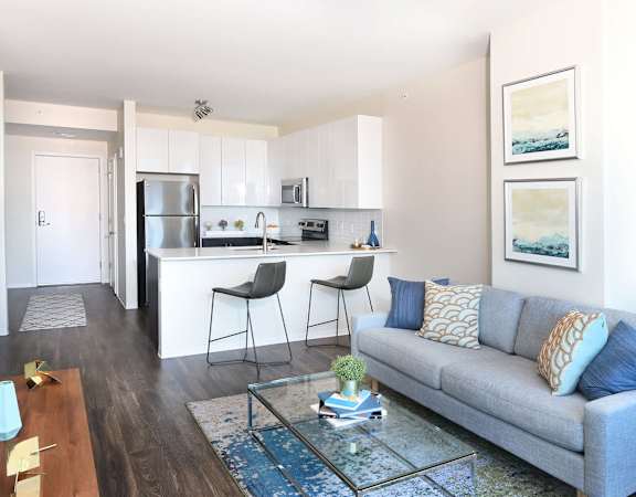 A modern living room with a grey couch and a glass coffee table.