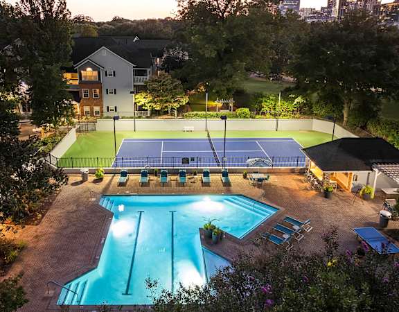 Aerial picture of resort-style swimming pool and lighted tennis court at dusk - Evergreen Lenox Park