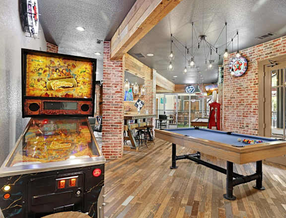 A room with a pool table and a pinball machine.
