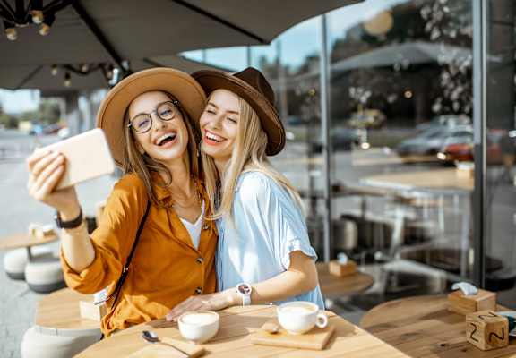 Two women taking a selfie in a cafe.