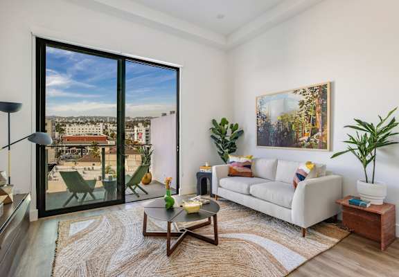 A living room with a large window overlooking a cityscape.at WM by CLG, Los Angeles, CA 90232