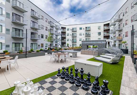 an apartment patio with tables and chairs and a large chess set at Northern Lights a Lifestyle-Driven Community, North Dakota