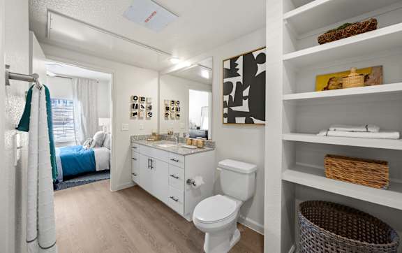 A white bathroom with a toilet, sink, and shelves. at Bridge at Tech Crossing, Austin