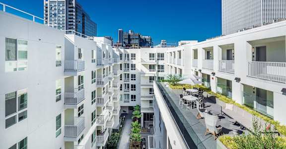 A white residential building with balconies and a small garden in the courtyard. at G12 Apartments, Los Angeles, CA, 90015