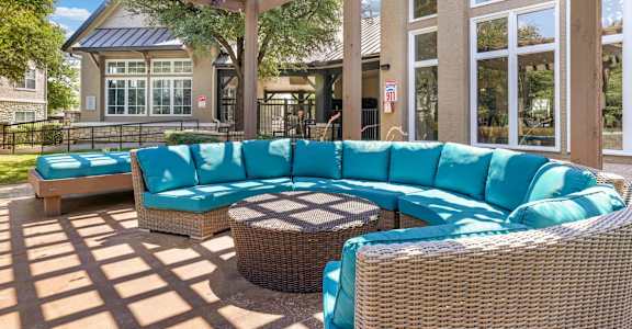 A patio with a blue couch and a wicker table.