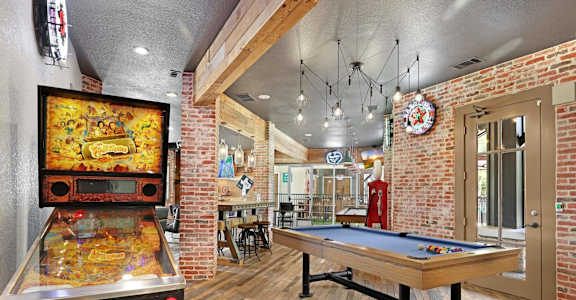 A room with a pool table and a pinball machine.