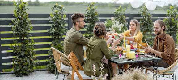 Four people toasting glasses at a table in a garden at 128 on State Apartments in Kirkland, Washington