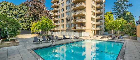 A large swimming pool in front of a tall apartment building.