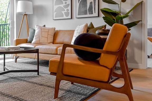 A yellow chair with a black bowl on it sits in a living room.