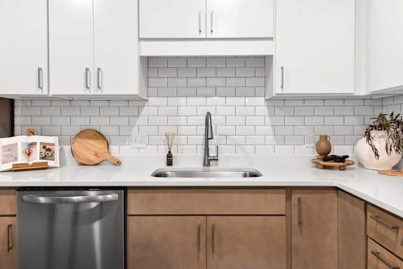 A kitchen with a stainless steel dishwasher and wooden cabinets.