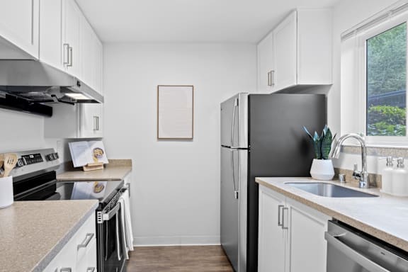 A kitchen with a black refrigerator and white cabinets.