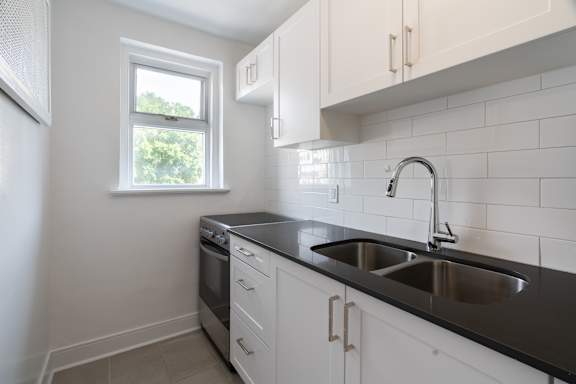 A kitchen with white cabinets and black countertops at 391 Sherbourne Apartments, Toronto, M4X 1K4