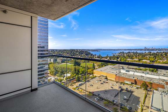 A balcony with a view of a parking lot and buildings.