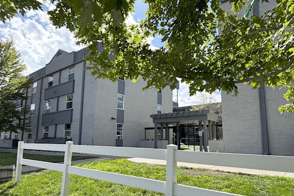 A white fence in front of a grey building.