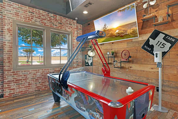 A red air hockey table in a room with a brick wall.