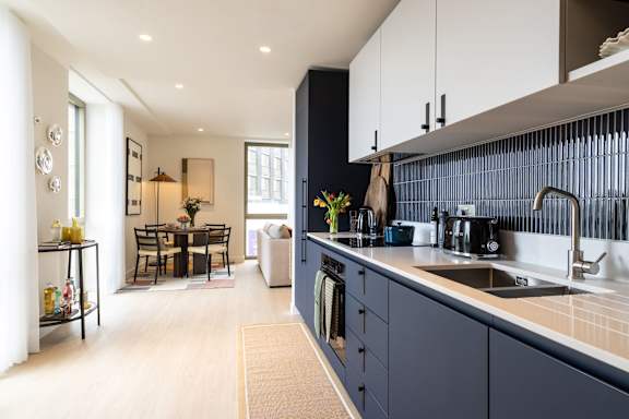 A modern kitchen with dark blue cabinets and a white countertop.