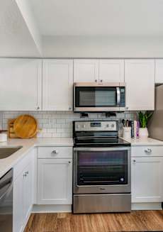 a kitchen with stainless steel appliances and white cabinets at The Villas at Ibis Landing, Parkland, FL