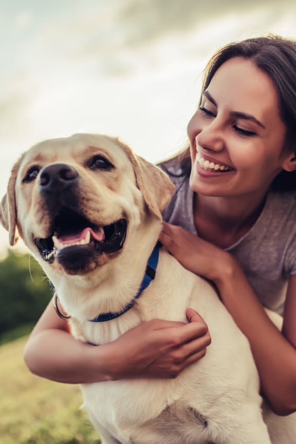 a woman is hugging her dog in a field