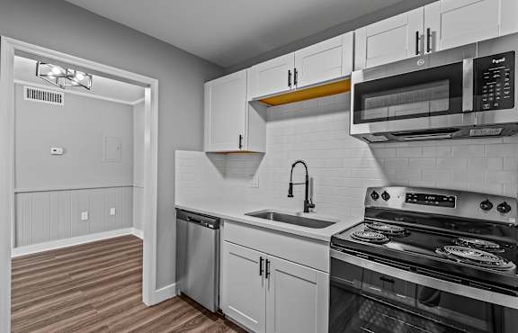 A kitchen with white cabinets and a black stove top oven. at Serenity Place Central, Tallahassee, FL
