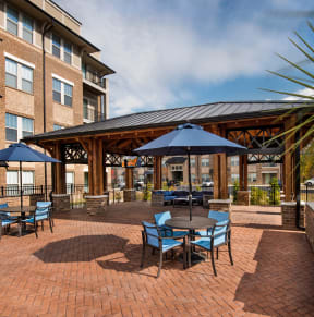 a patio with tables and umbrellas in front of an apartment building at Residence at Riverwatch in Augusta, GA 30909