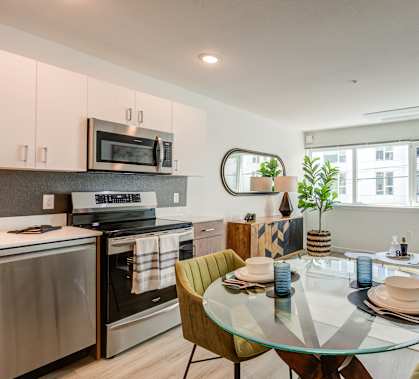 A modern kitchen with a glass dining table set for two at THE MOD AT MIDTOWN Apartments, 95814