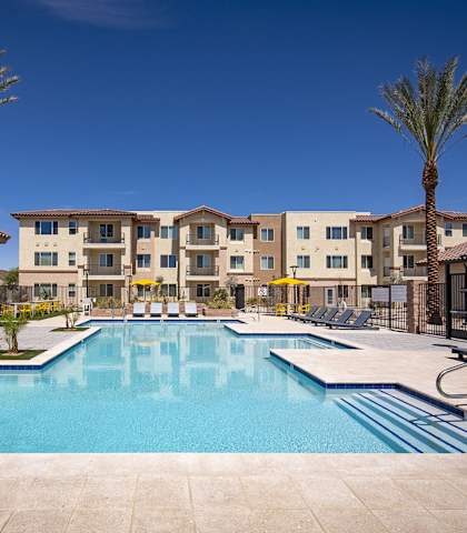 A large swimming pool in front of a building with palm trees. at The Safford Apartments, Marana, AZ