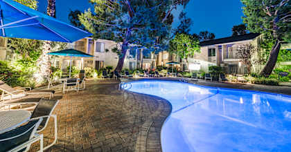 a swimming pool with chairs and umbrellas at night