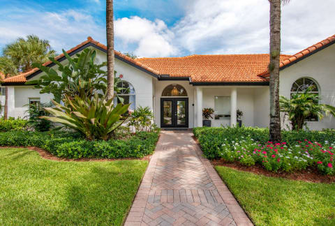 a house with a walkway and palm trees at The Villas at Ibis Landing, Parkland