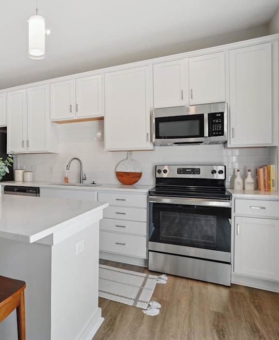 A kitchen with white cabinets and a white island with a counter top. at Zora University, Charlotte