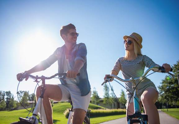 A man and a woman are riding bicycles on a sunny day.