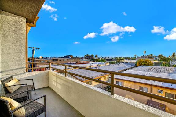 A balcony with a chair and a table overlooking a residential area at Twelve One Ten Rochester, Los Angeles, 90025