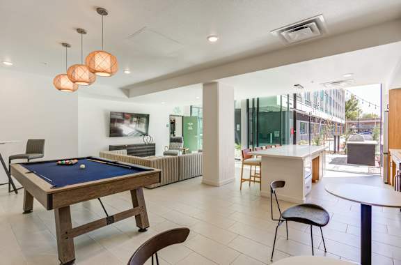 A pool table is in the middle of a room with a bar and chairs at THE MOD AT MIDTOWN Apartments, California
