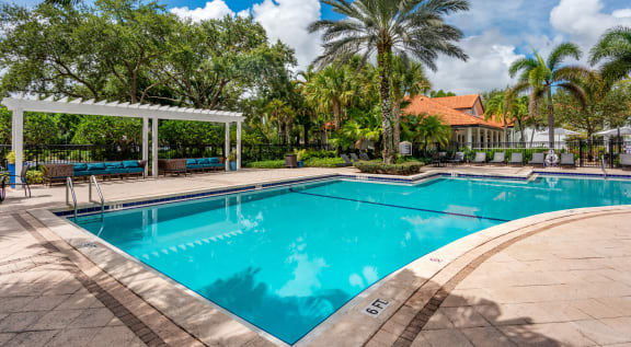 a swimming pool with palm trees and a building in the background at The Villas at Ibis Landing, Florida