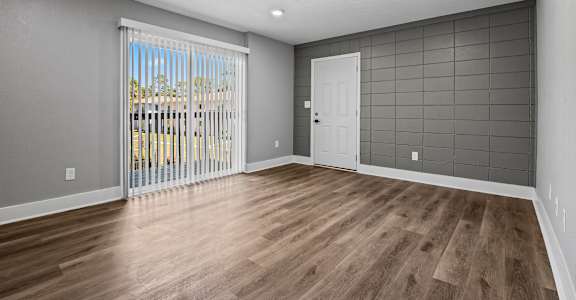 A room with wooden floors and a sliding glass door leading to a balcony. at Serenity Place Central, Tallahassee, FL, 32304