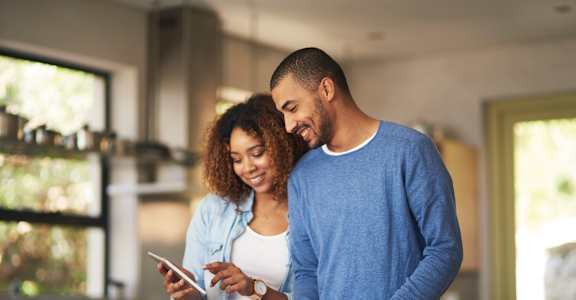 a man and woman standing in a kitchen looking at a cell phone at Beau Chene Lake Charles Apartments, Lake Charles, Los Angeles