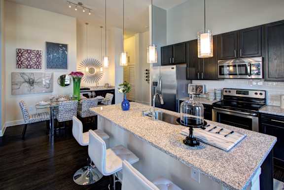 A kitchen with a granite countertop and white chairs.