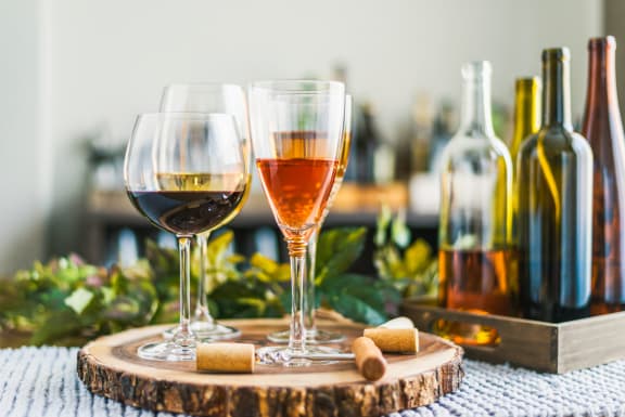 two glasses of wine on a table next to bottles of wine