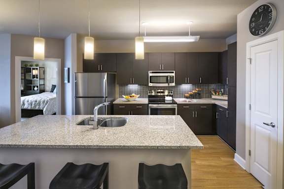 A modern kitchen with a granite countertop and black bar stools.
