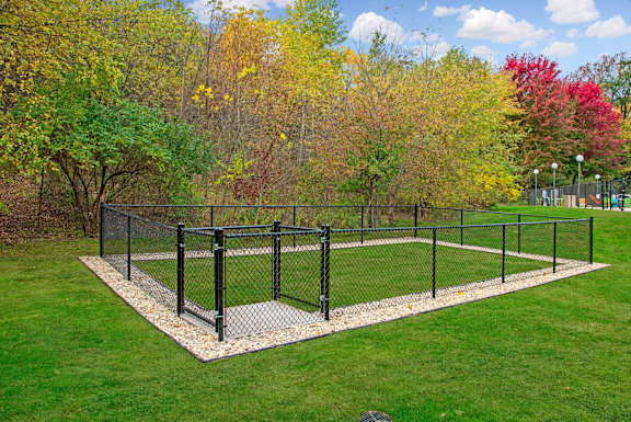 a fenced in tennis court in the middle of a park