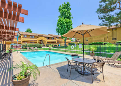 A pool area with a table and chairs and a patio umbrella.