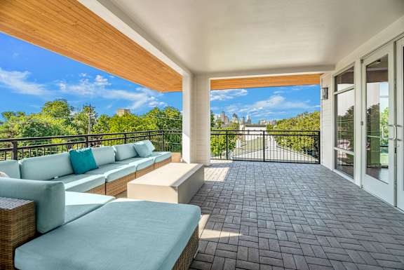 A balcony with a couch and pillows overlooking a city.
